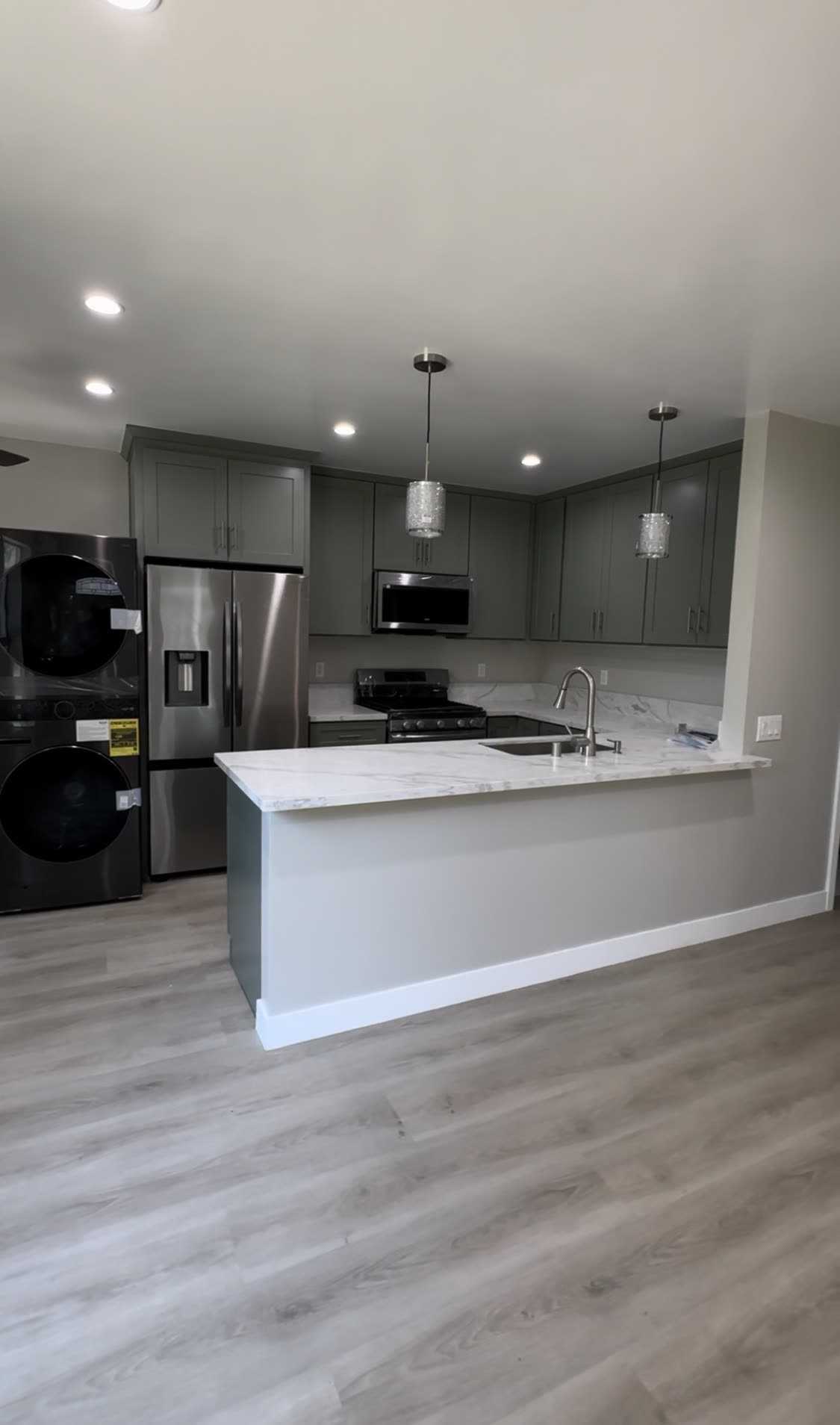 Sage green kitchen with marble waterfall peninsula