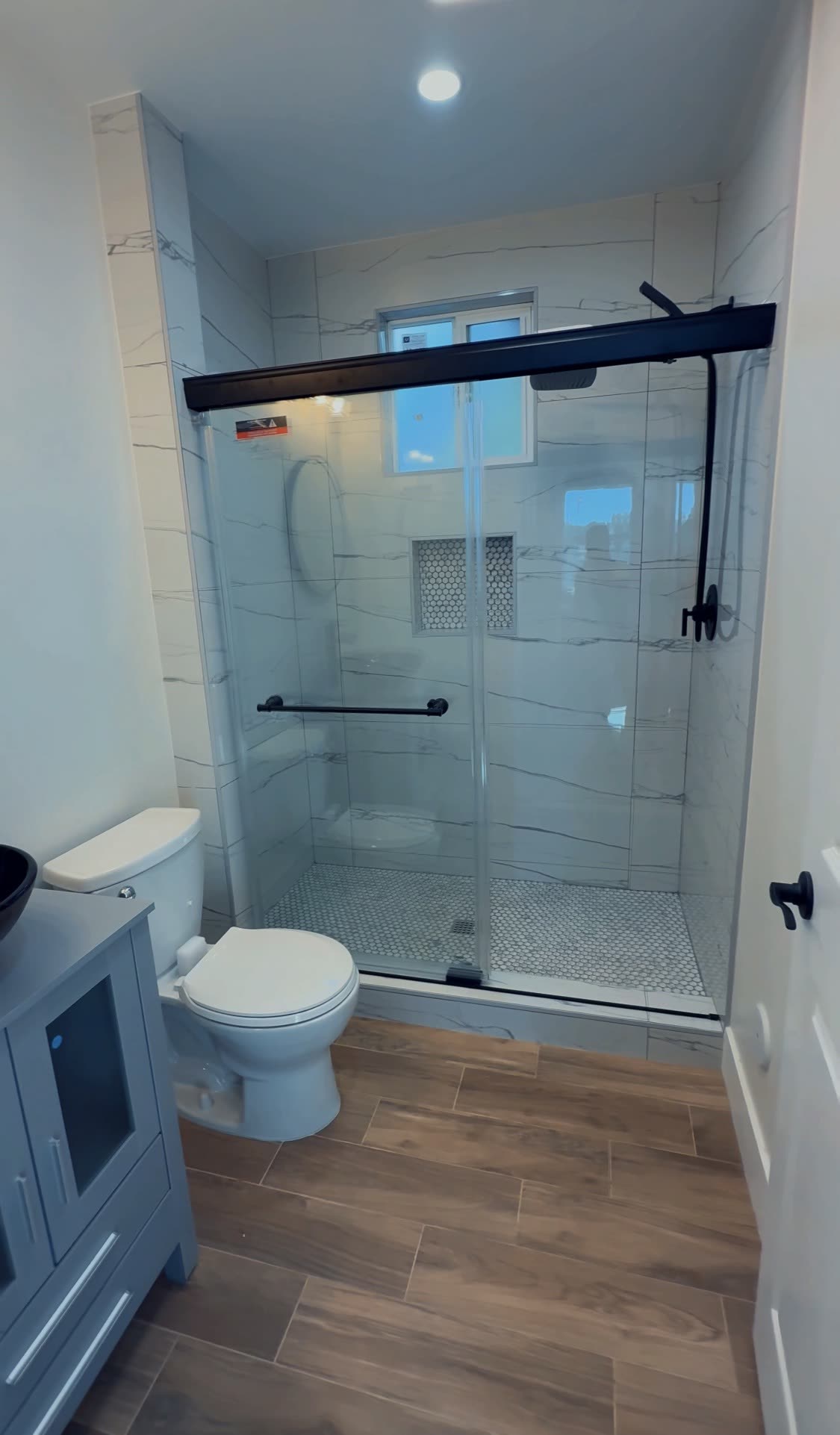 Marble tiled shower with black framed sliding glass door