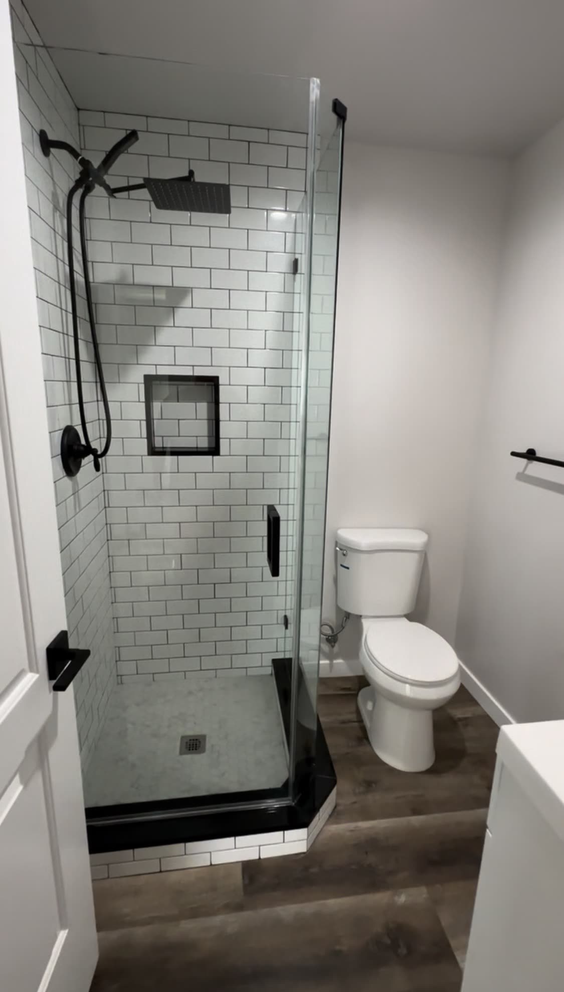 Walk-in shower with white subway tile and black hardware