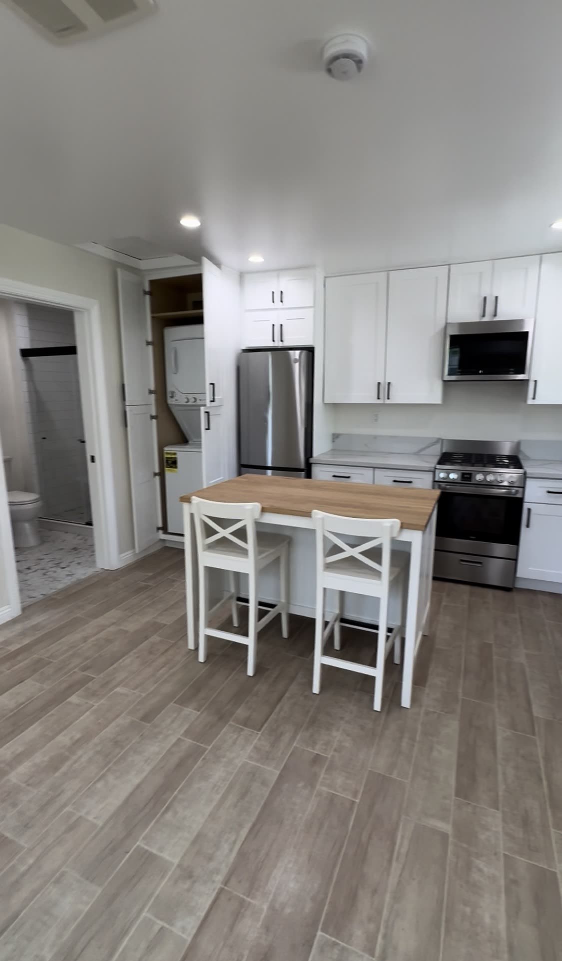 Finished ADU interior with white kitchen, butcher-block island and in-unit laundry