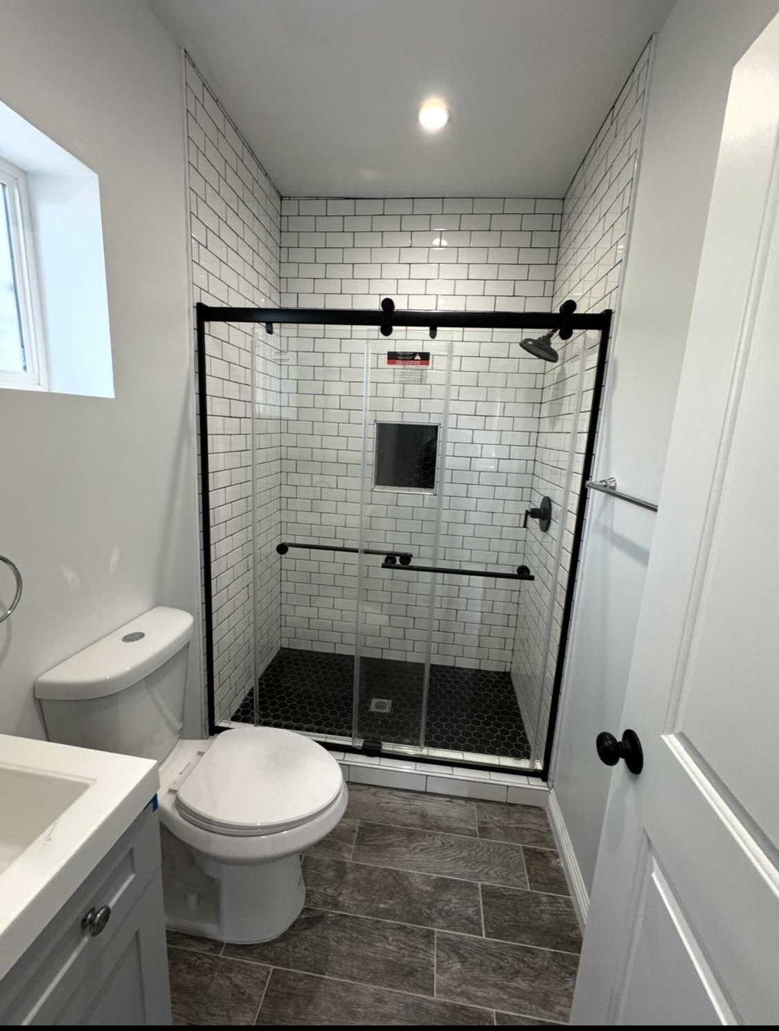 Bathroom with black hexagon floor tile and white subway walls