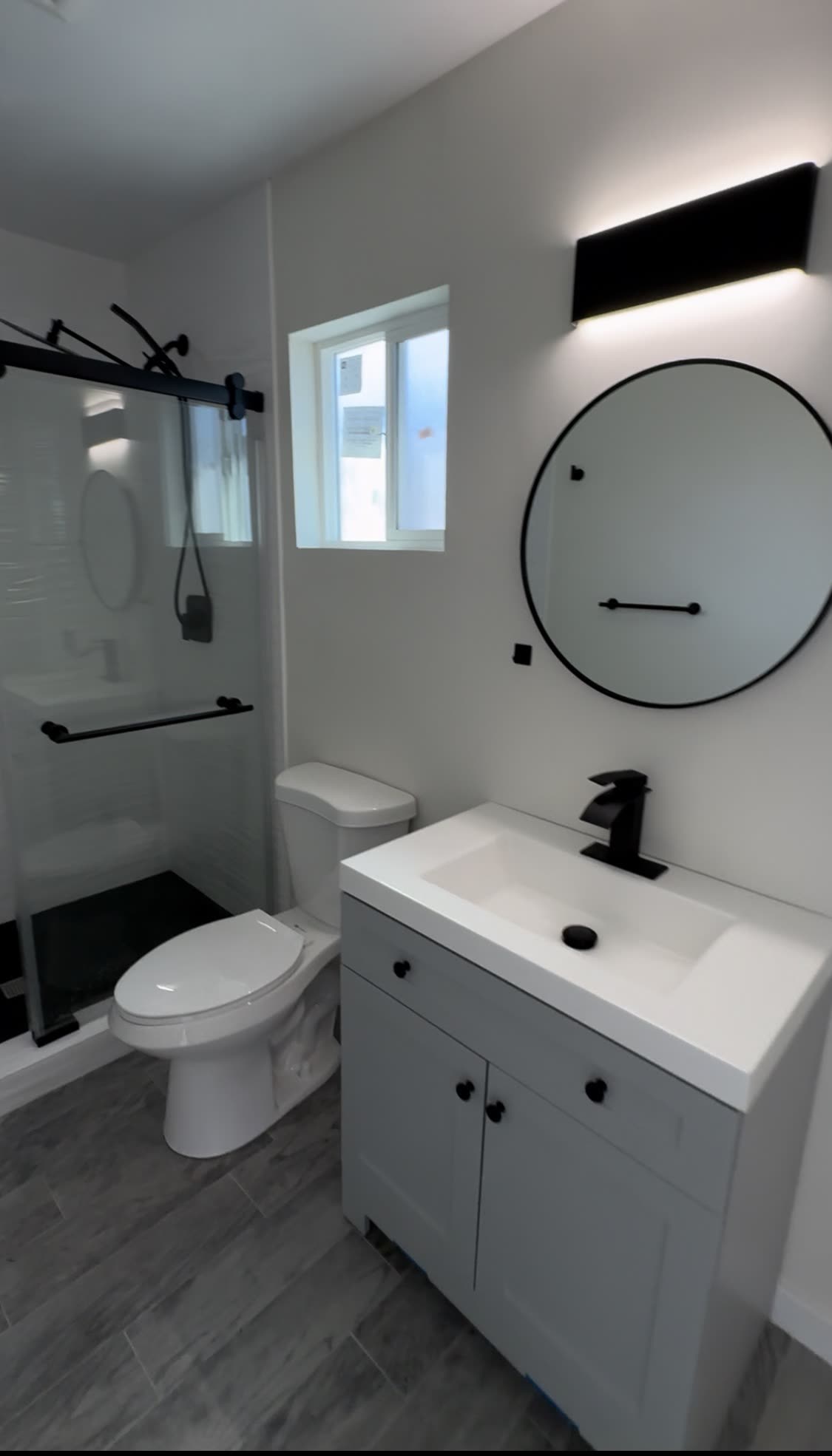 Bright bathroom with round mirror and marble shower